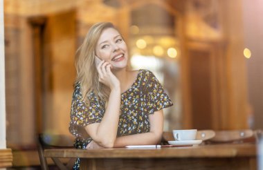 Café'de akıllı telefon kullanan güzel genç kadın