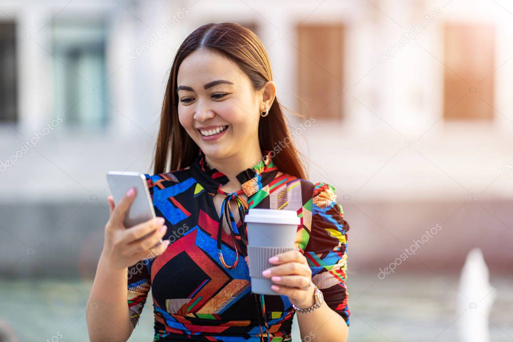 Attractive young woman with smartphone and coffee in the city 