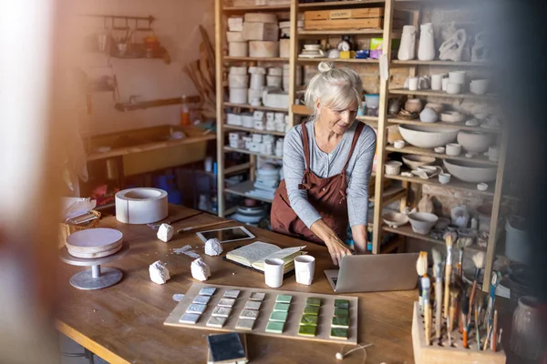 Mujer Madura Artista Cerámica Utilizando Ordenador Portátil Estudio Arte —  Fotos de Stock