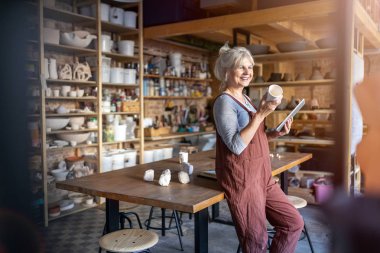 Senior craftswoman with tablet computer in art studio 