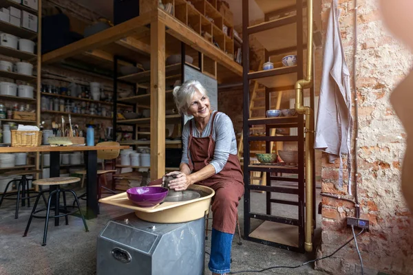 用陶工的轮作陶瓷制品的老年妇女 — 图库照片