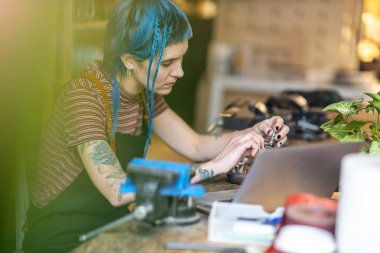 Genç bir kadın atölyesinde dizüstü bilgisayar kullanıyor.