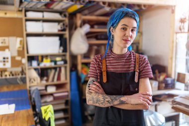 Confident young craftswoman in her workshop clipart