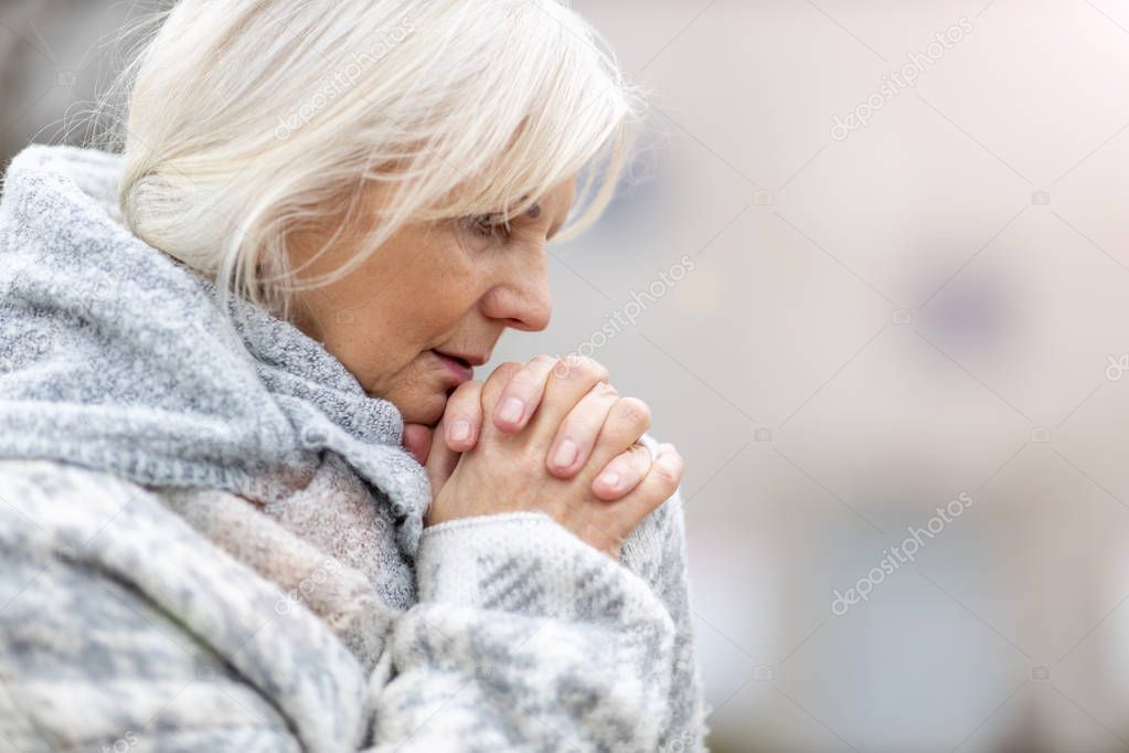 Portrait of senior woman praying 