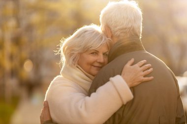 Senior couple hugging outdoors in autumn