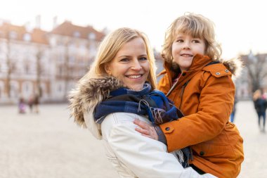 Anne ve küçük sevimli oğlu dışarıda sarılıyorlar.