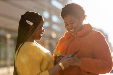 Mutlu bayan arkadaşlar şehirdeki akıllı telefonlarıyla mesaj yolluyor.