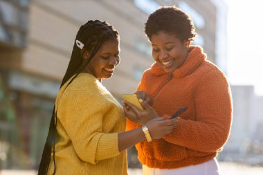 Mutlu bayan arkadaşlar şehirdeki akıllı telefonlarıyla mesaj yolluyor.