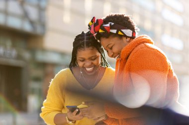 Mutlu bayan arkadaşlar şehirdeki akıllı telefonlarıyla mesaj yolluyor.