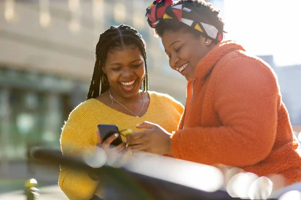 快乐的女性朋友在城市里用她们的智能手机传递信息 — 图库照片