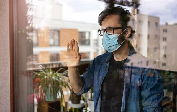 Man Med Ansiktsmask Tittar Genom Fönstret — Stockfoto