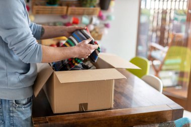 Evdeki adam elbiseli paketleri açıyor.