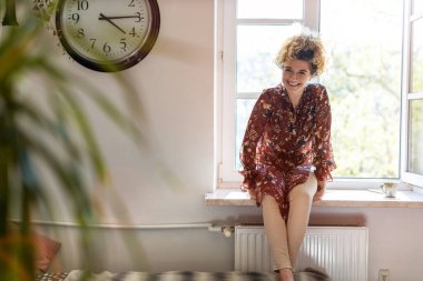 Pencere pervazında oturan genç kadın.