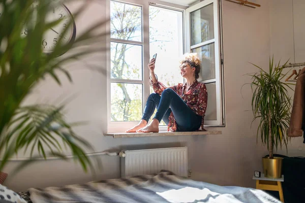 Young Woman Sitting Window Sill Using Smartphone — Stock Photo, Image