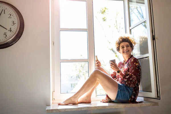 Young Woman Sitting Window Sill Using Smartphone — Stock Photo, Image