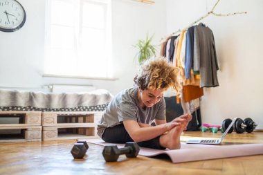 Evde spor yapan genç bir kadın.