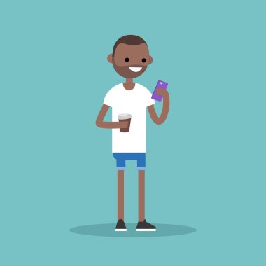Genç siyah adam manifatura onun akıllı telefon ve bir fincan holding 