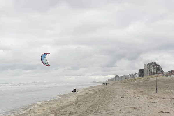 Oostduinkerke, Belçika - 26 Şubat 2020: Soğuk ve rüzgarlı bir günde Kitesurfer plajda dinleniyor