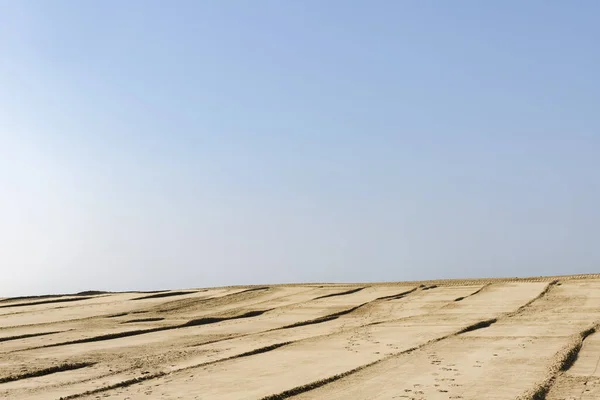 Mavi gökyüzü ve kumla minimalist bir manzara.