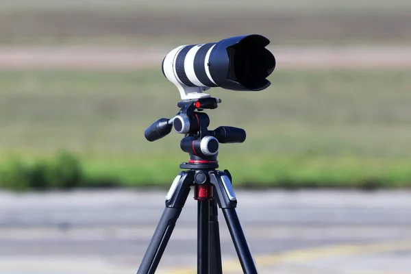 Professional telephoto lens for DSLR camera on the tripod, close-up