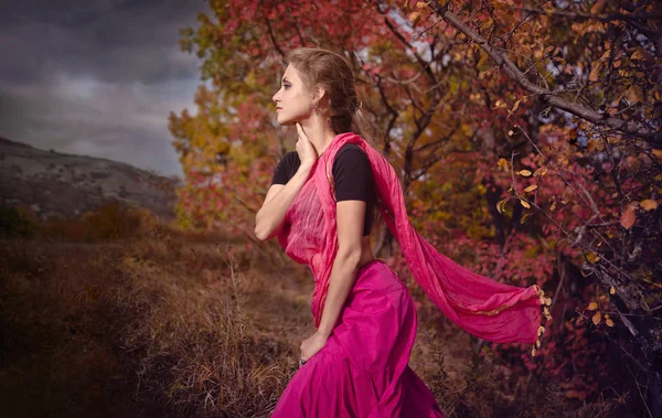 Autumn landscape, a girl walks alone at the foothills of the mountains under fall foliage