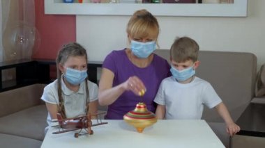 Annem tıbbi maskeli çocuklara eski bir bluzun nasıl döndürüleceğini gösteriyor. COVID-19 salgını sırasında karantinada sosyal mesafeler ve kendini izole etme.
