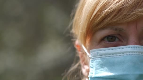 Un ritratto ragazza chiudere mezza faccia personaggio serie lo sfondo di un albero in fiore. Il concetto di protezione dall'infezione da COVID-19 coronavirus . — Video Stock