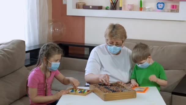 Babcia uczy dzieci liczyć na stare konta w pokoju. Odległość społeczna i izolacja w czasie kwarantanny podczas pandemii COVID-19. — Wideo stockowe