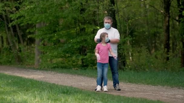 Pai e filha em máscaras médicas e luvas de borracha giram no Parque da Primavera. O conceito de proteção da infecção por coronavírus covid-19 . — Vídeo de Stock