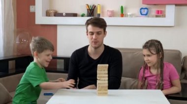Ağabeyin Jenga Masası oyununda çocuklarla oynuyor. COVID-19 salgını sırasında karantinada sosyal mesafeler ve kendini izole etme.