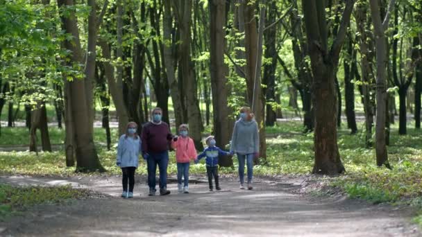 2人の娘は春に医療マスクで公園を歩く Covid 19コロナウイルス感染からの保護の概念 — ストック動画