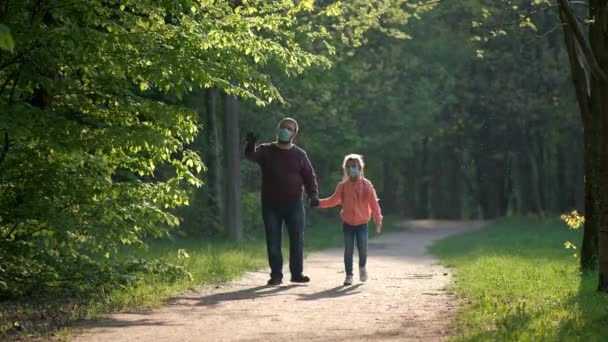 今年春天 爸爸和女儿戴着口罩和橡胶手套在公园里散步 Covid Coronavirus感染防护概念 — 图库视频影像