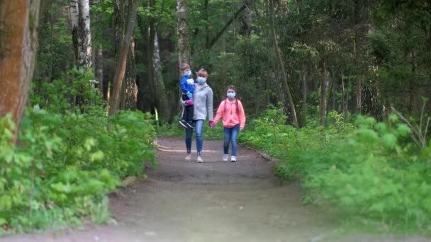 Sağlık Maskeli Bir Aile Ilkbaharda Parkta Yürür Anne Oğlunu Kollarında — Stok video
