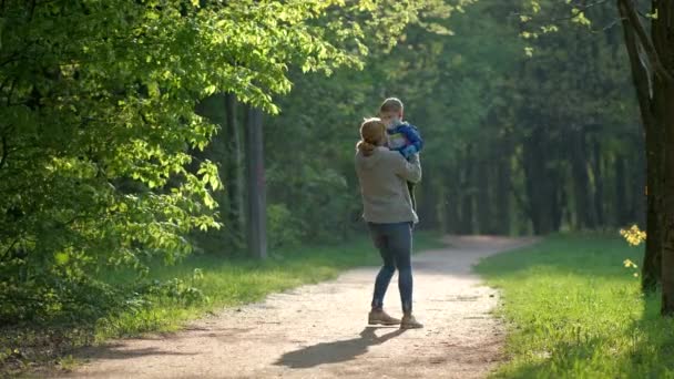 戴着口罩和橡胶手套的母子们在春天的公园里旋转着 Covid 19病毒感染防护的概念 — 图库视频影像