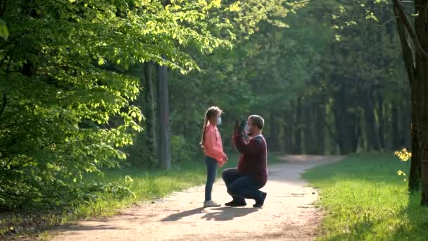 父亲和女儿戴着口罩和橡胶手套在春天的公园里旋转 Covid 19病毒感染防护的概念 — 图库视频影像