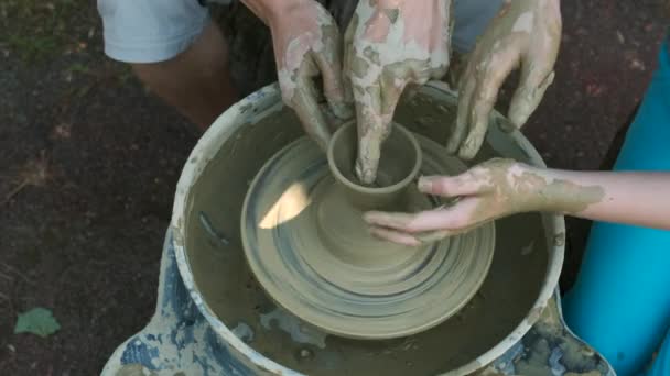 波特大师教孩子用电动汽车在现代波特的轮子上做一个陶罐 一个小孩和一个成年男人的手都沾满了泥土 教陶器 — 图库视频影像