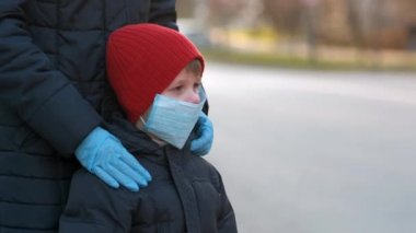 Anne, Avrupa 'nın bir şehrinde küçük oğlu için koruyucu tıbbi maskeyi ayarlıyor. Çin koronavirüsüne karşı koruma 