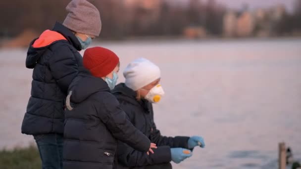 戴着口罩的母女俩在湖边的公园里喂鸭子 发生大流行病时援助动物的概念 — 图库视频影像