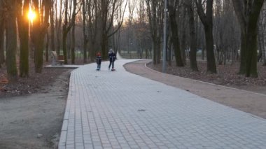 Maskeli küçük bir çocuk ve kız parkta scooter kullanıyor. Ncov-19 Coronavirüsüne Karşı Koruma