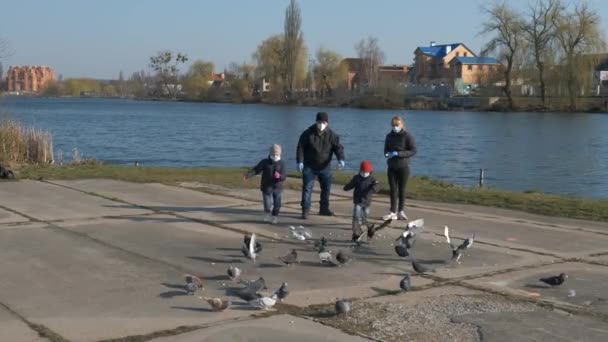 医者のマスクの男の子と女の子はハトの群れを通って実行されます 湖の公園で 鳥が飛び去る スローモーションクリップ — ストック動画