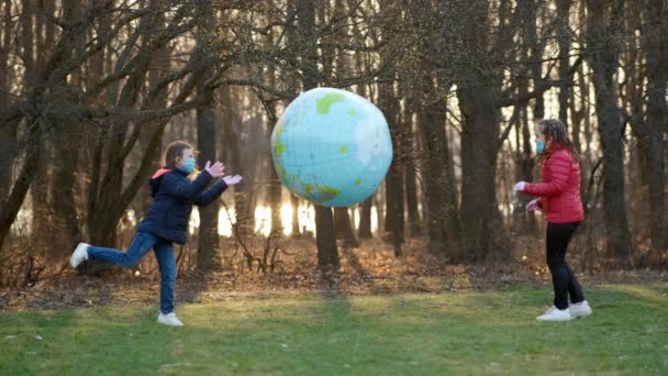 Två Flickor Medicinska Masker Leker Vårparken Med Stor Uppblåsbar Bollplanet — Stockvideo