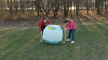 İki küçük kız şişme top gezegeni Dünya 'ya gazlı bez maskesi taktı. Koronavirüs enfeksiyonlarına karşı koruma kavramı covid-19.