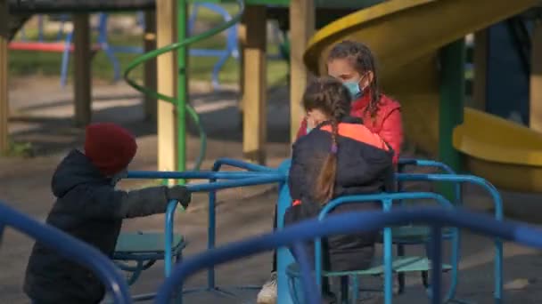 Drie Kinderen Met Medische Maskers Rijden Een Draaimolen Speelplaats Het — Stockvideo