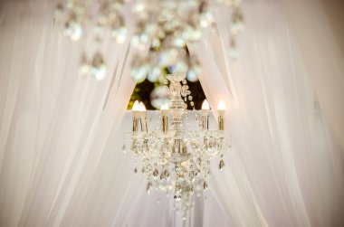 Beyaz şömineli, beyaz şömineli, çiçeklerle süslü beyaz elbiseli ve her iki taraftaki misafirler için tahta sandalyeli düğün yeri..