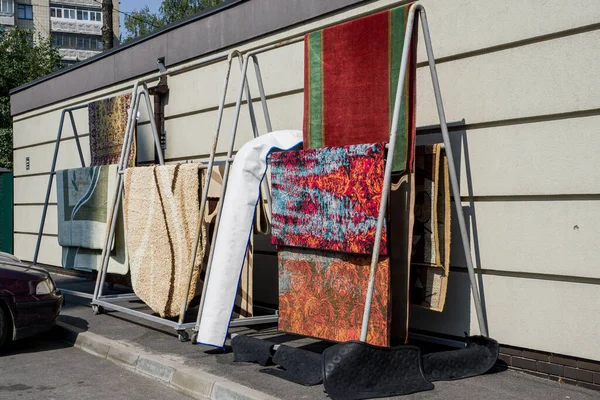 Dışarıdaki raflarda farklı halılar asılı. Profesyonel halı temizleme ve kurutma..