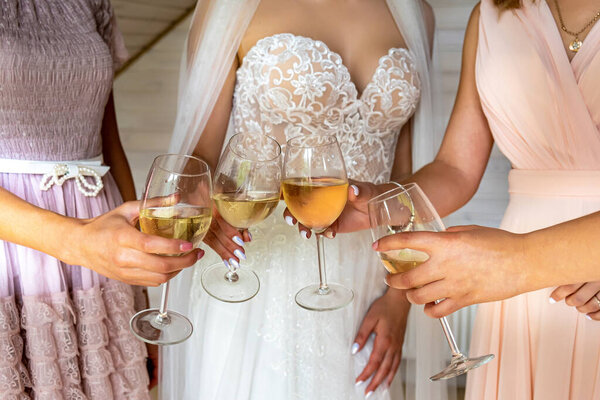 Невеста и свидетели держат бокалы шампанского в отеле. Руки с очками.