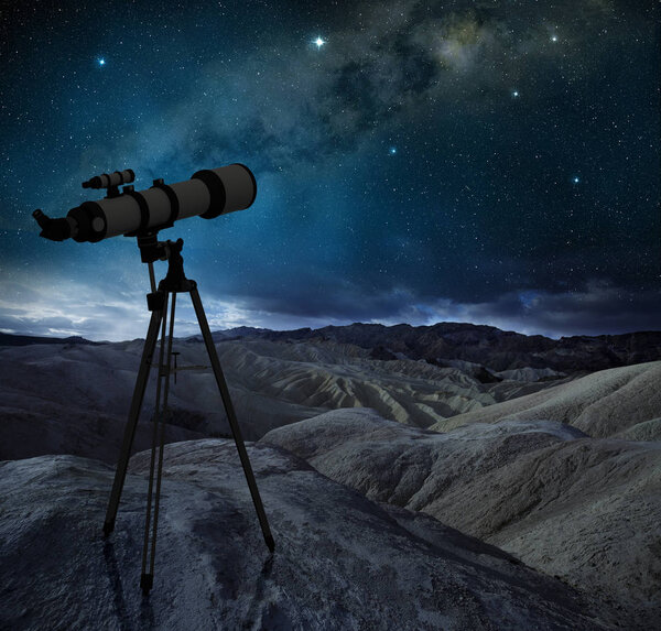 telescope tripod pointing the milky way in a desert landscape 