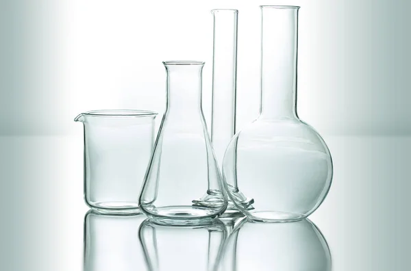 Set of chemical glassware on reflective surface — Stock Photo, Image