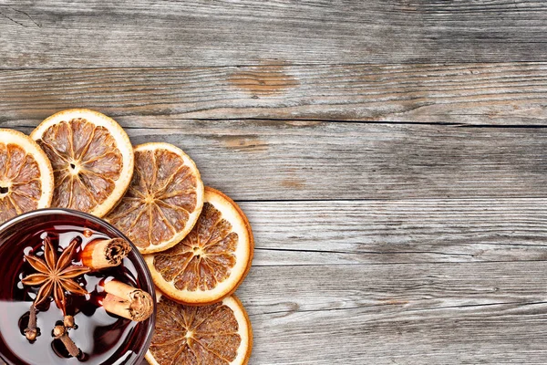 Glühwein und Orangenscheiben auf rustikalem Holzgrund — Stockfoto