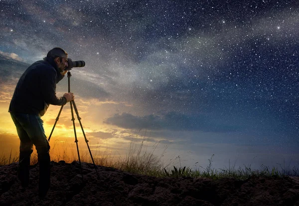 Homem tirando uma foto ao amanhecer com céu estrelado — Fotografia de Stock